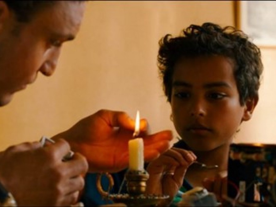 A person lighting a candle with a child