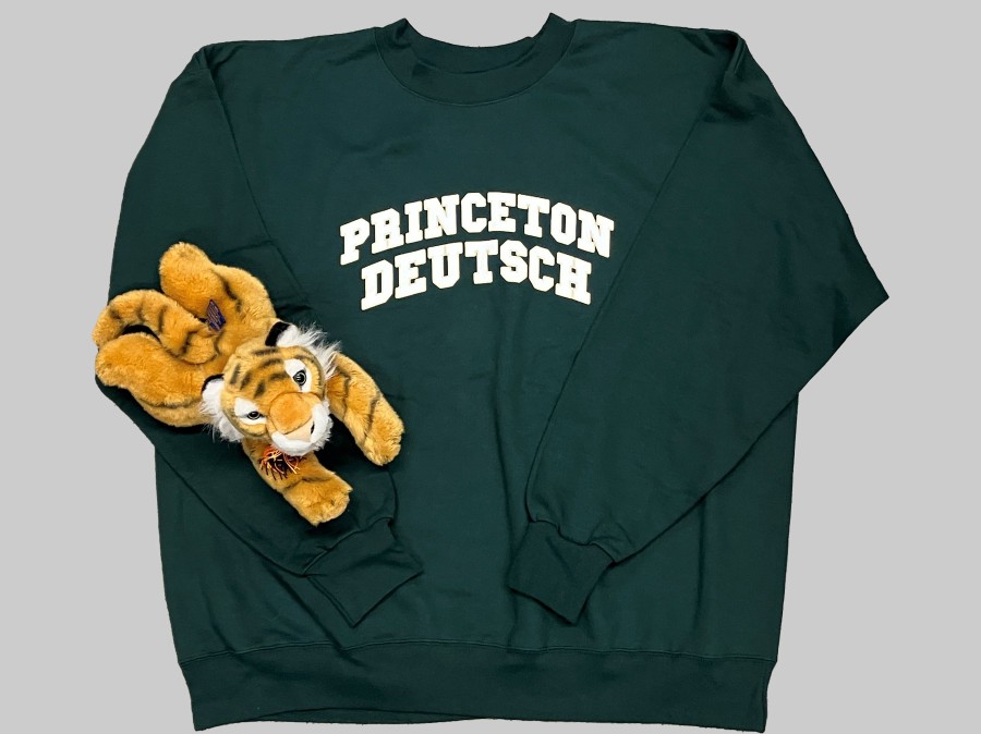 Stuffed tiger on arm of green sweatshirt with Princeton Deutsch text
