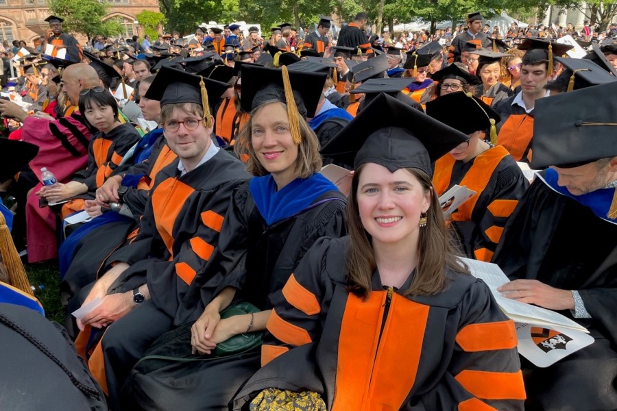 Princeton Grads Hooding ceremony with smiling people sitting wearing collegiate gowns