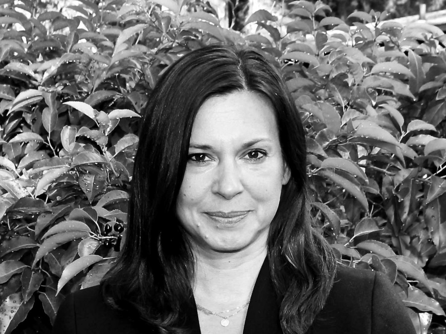 Portrait of Sonja Boos with shrubs behind her.