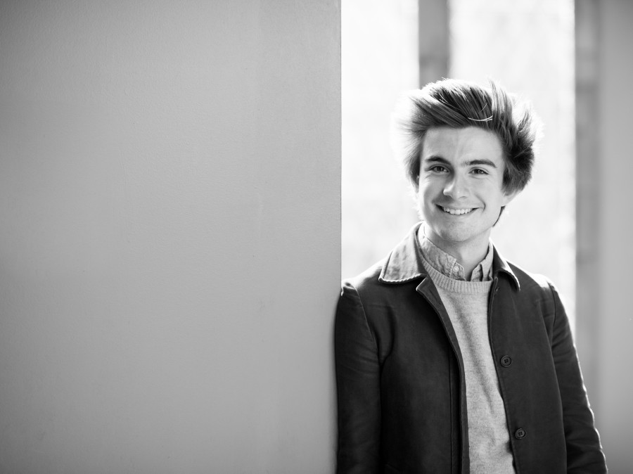 Student smiling as leaning against hallway wall doorway