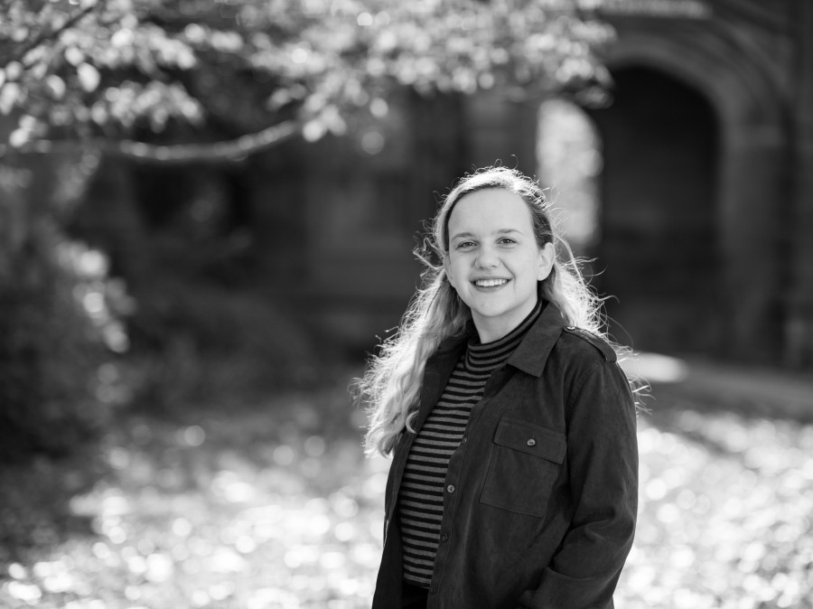 Student in foreground with foliage and archway in background