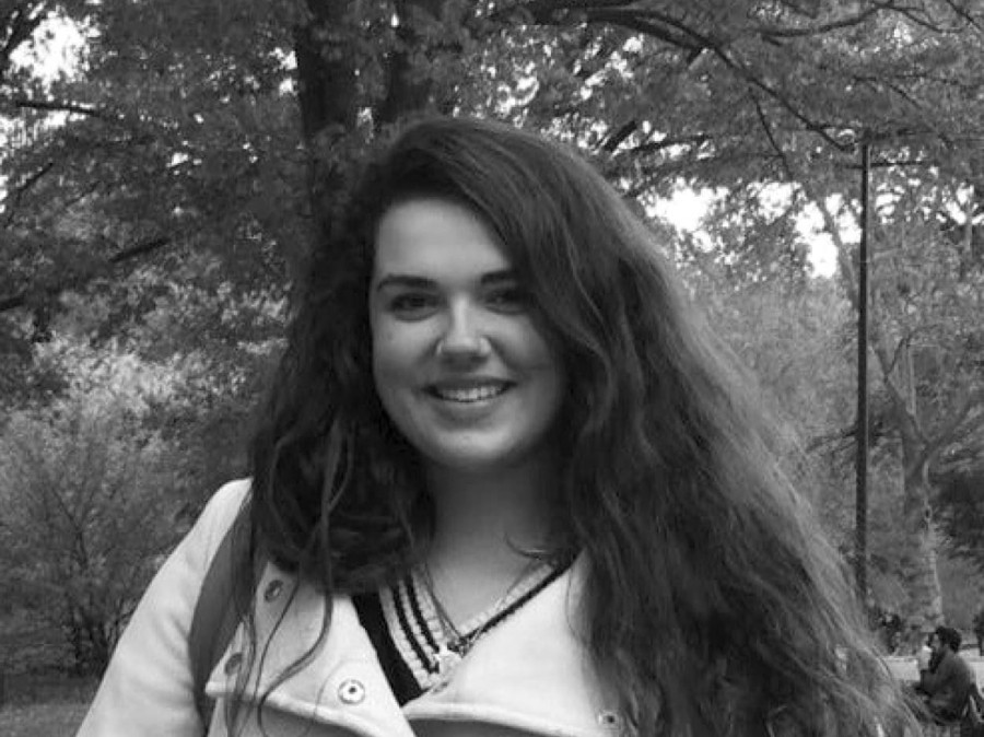 Student smiling with trees and campus setting in background