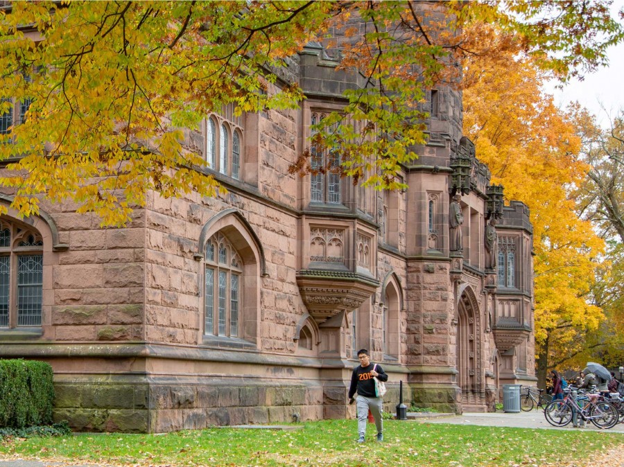Campus building with student walking away in a Fall setting