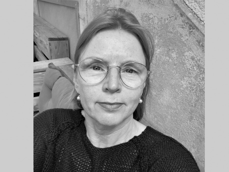 Faculty member wearing glasses with stone wall in background