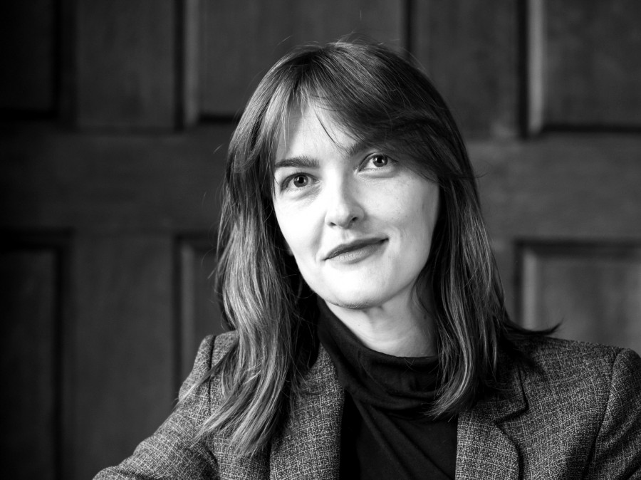 Female faculty member with sport coat with raised wood panels in background