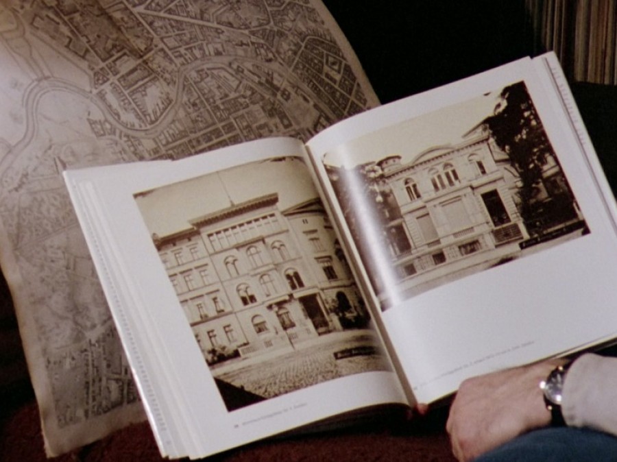 Open book with building and person's arm that is reading it.