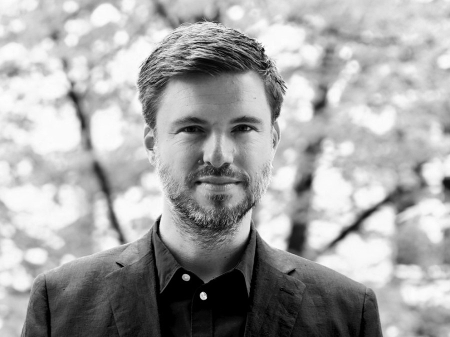 Man standing wearing a sport coat with trees blurred in background