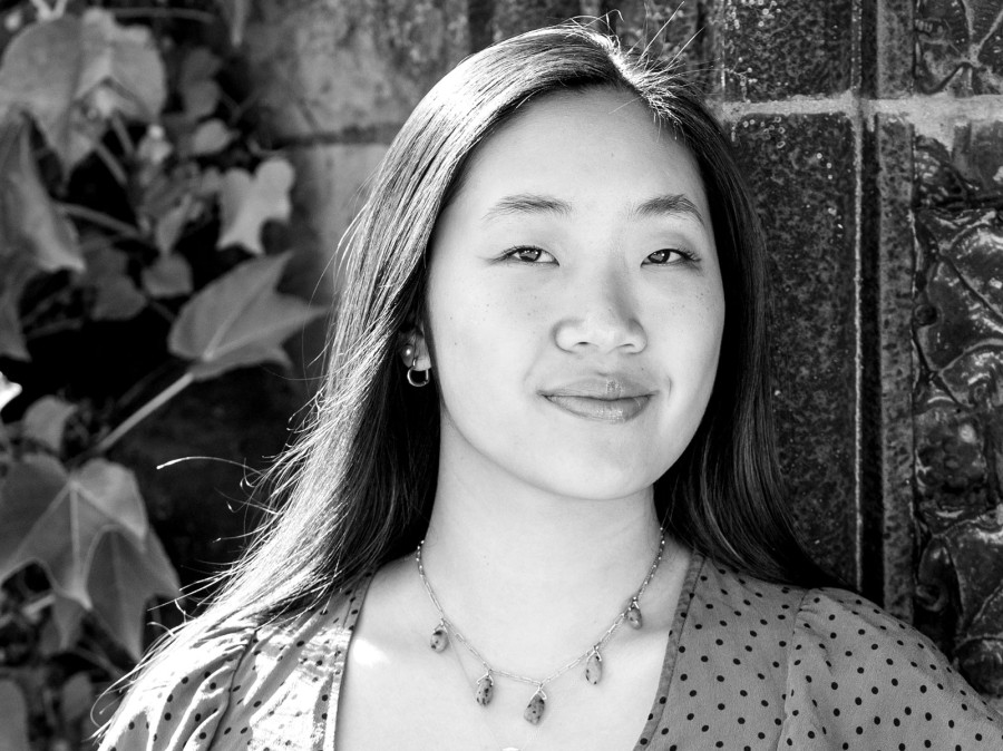 Student smiling with building and ivy vines directly behind 