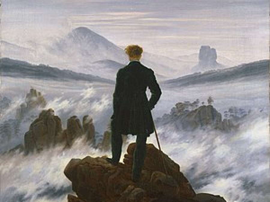 Man standing alone on a hilltop with back toward viewer