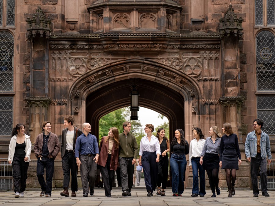 Grad students standing in East Pyne Courtyard with arch in background.