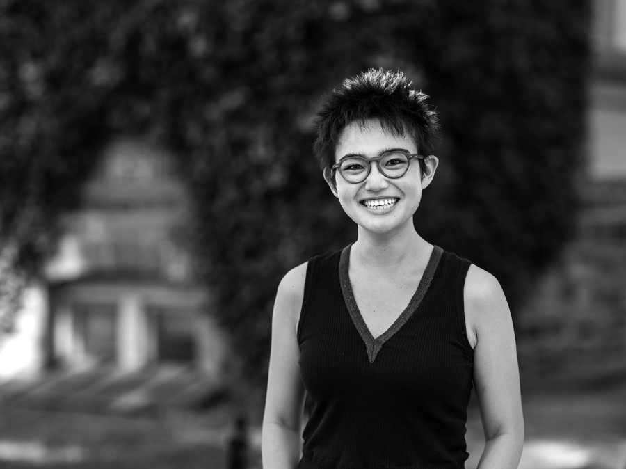 Student infront of blurred background of ivy-covered structure