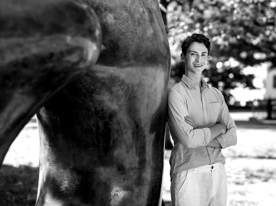 Student leaning against sculpture on campus