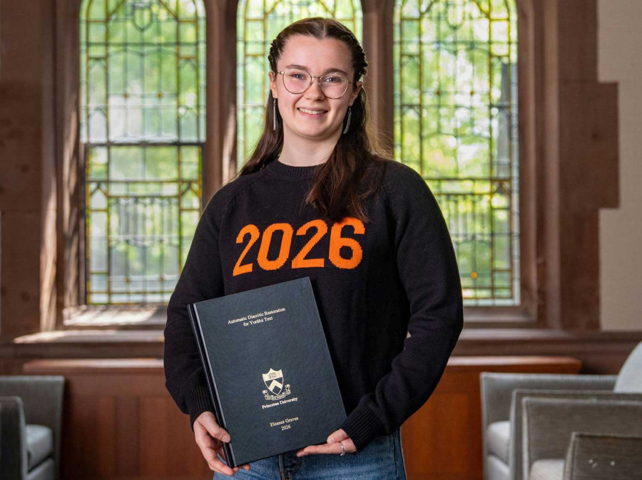 Student holding award infront of collegiate window setting