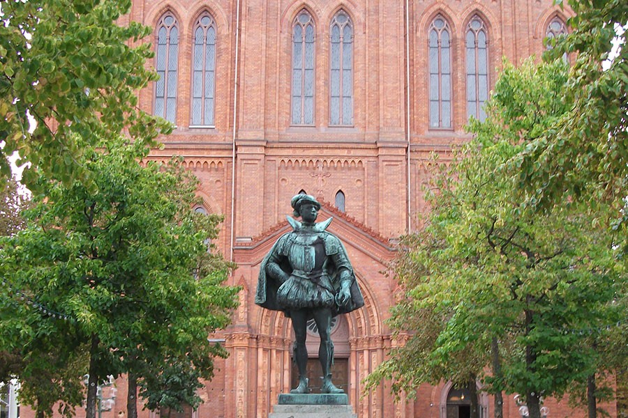 Building with ornate statue in front, trees on both sides