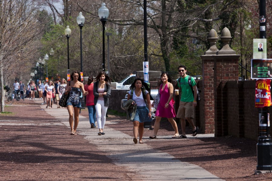 Students walking on sidewalk to campus in summer attire.