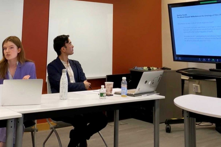 Two students in conference with one looking at screen