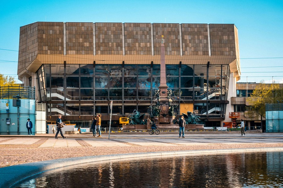 Fountain in foreground with people standing out front awaiting train