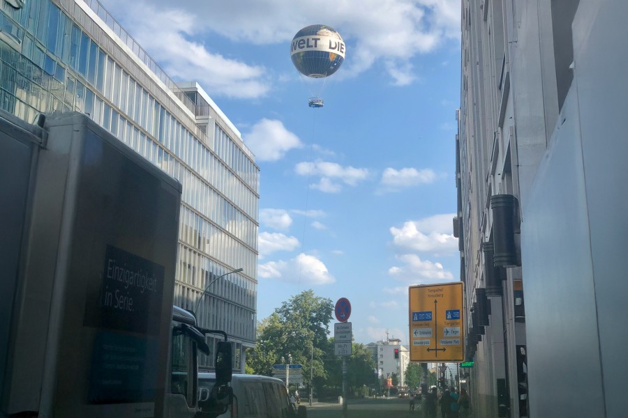 Balloon tethered in city with street in foreground and buildings