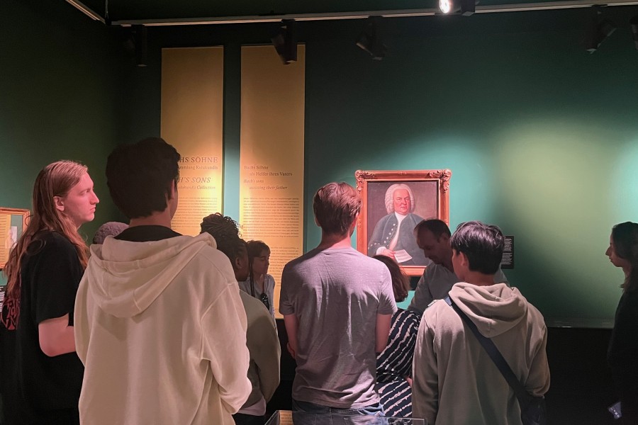 Students in room looking at framed picture on wall.
